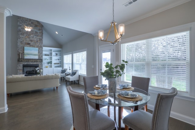 dining area with dark hardwood / wood-style floors, an inviting chandelier, a stone fireplace, and vaulted ceiling