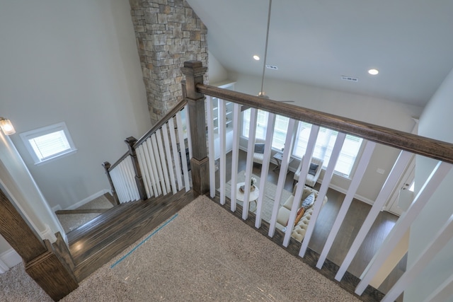 stairway featuring plenty of natural light, high vaulted ceiling, and dark carpet