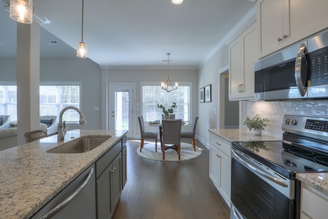 kitchen featuring pendant lighting, appliances with stainless steel finishes, white cabinetry, dark hardwood / wood-style floors, and sink