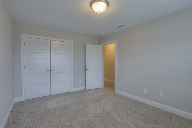 unfurnished bedroom with light carpet and a closet