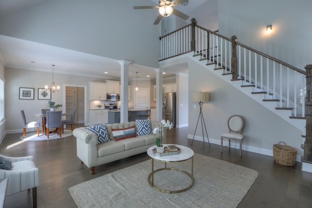 living room with a high ceiling, dark hardwood / wood-style flooring, ceiling fan with notable chandelier, and decorative columns