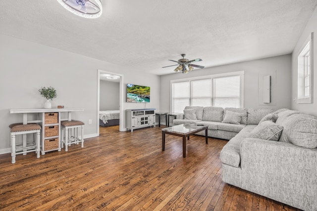 living room with ceiling fan, a healthy amount of sunlight, a textured ceiling, and dark hardwood / wood-style flooring