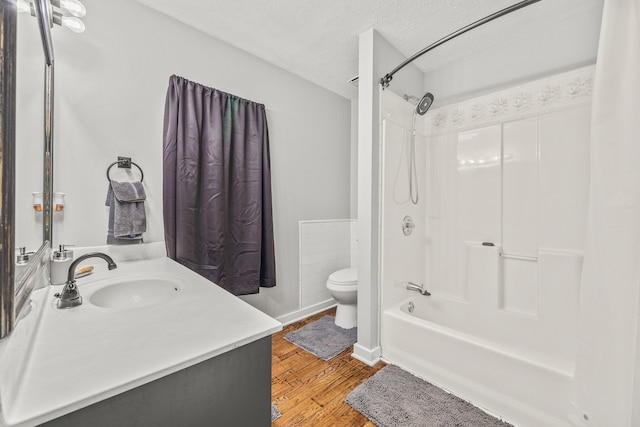 full bathroom with bathing tub / shower combination, a textured ceiling, toilet, vanity, and hardwood / wood-style flooring