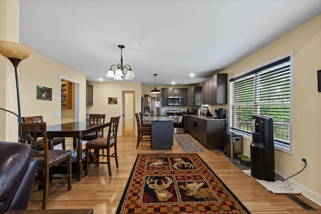 dining room with a notable chandelier, sink, and light hardwood / wood-style flooring