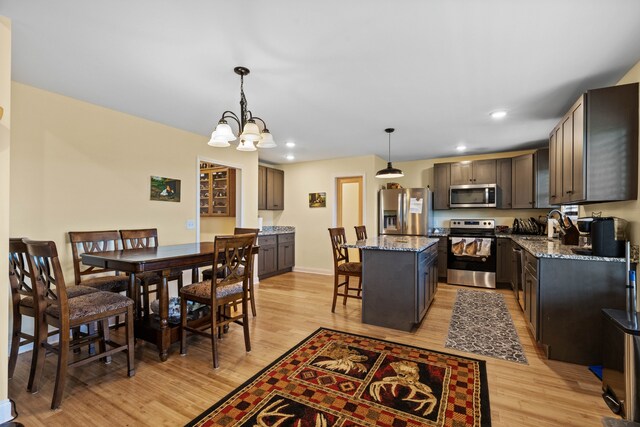 dining room featuring sink, a chandelier, and light hardwood / wood-style flooring