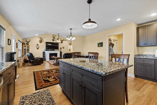 kitchen featuring a notable chandelier, dark stone counters, a kitchen island, and light wood-type flooring