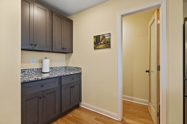 interior space featuring dark stone counters, dark brown cabinetry, and light hardwood / wood-style floors