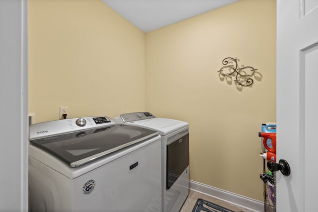 clothes washing area featuring light tile floors and washing machine and clothes dryer