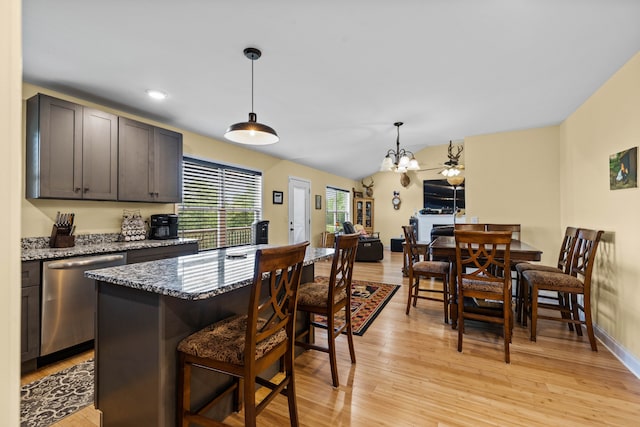 kitchen with light hardwood / wood-style flooring, dark stone counters, a breakfast bar, and dishwasher