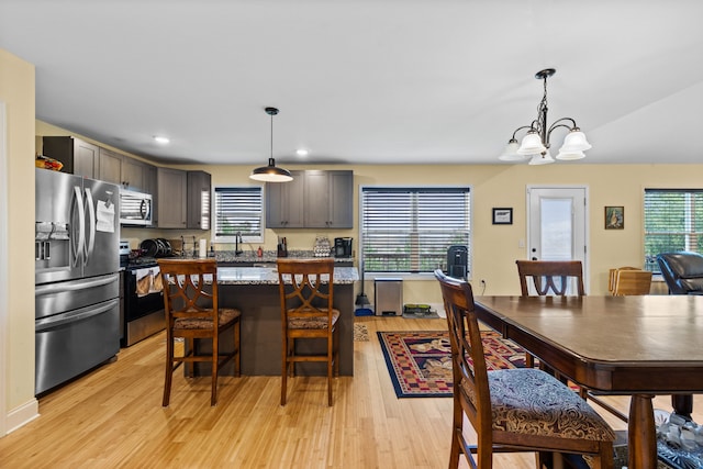 kitchen with light wood-type flooring, a chandelier, stainless steel appliances, and pendant lighting