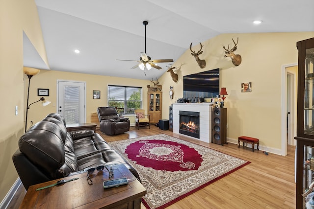 living room featuring ceiling fan, light hardwood / wood-style floors, and vaulted ceiling