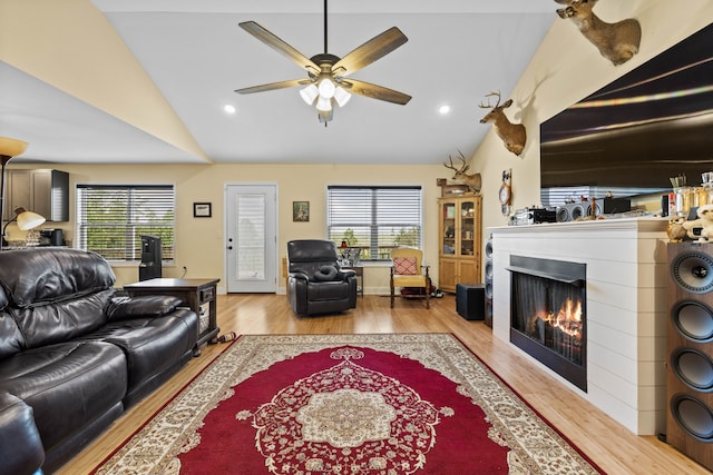 living room featuring lofted ceiling, light hardwood / wood-style floors, ceiling fan, and a wealth of natural light