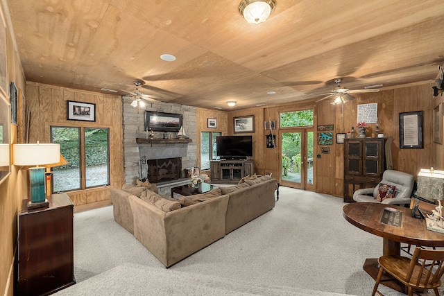 living room featuring light carpet, plenty of natural light, ceiling fan, and a stone fireplace