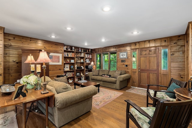 living room featuring built in features, light wood-type flooring, and wooden walls