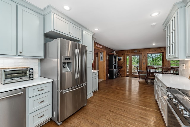 kitchen with french doors, stainless steel appliances, wood walls, dark wood-type flooring, and tasteful backsplash