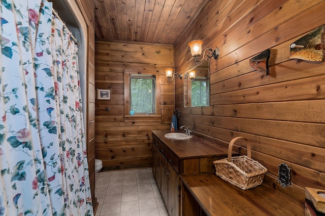 bathroom with wooden walls, vanity, tile floors, and toilet