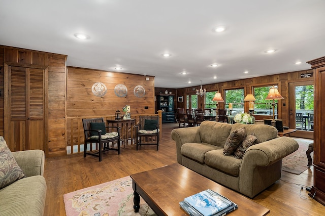 living room featuring wooden walls, a notable chandelier, and wood-type flooring