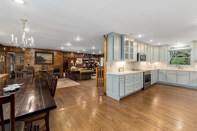 kitchen with pendant lighting, stainless steel appliances, an inviting chandelier, hardwood / wood-style floors, and sink