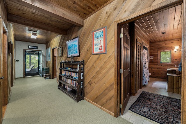 corridor with wooden walls, light colored carpet, wood ceiling, and beam ceiling