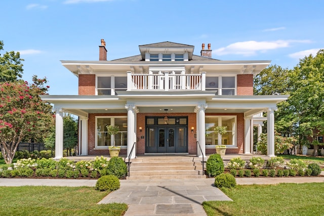 view of front of property featuring a front lawn, a balcony, and covered porch