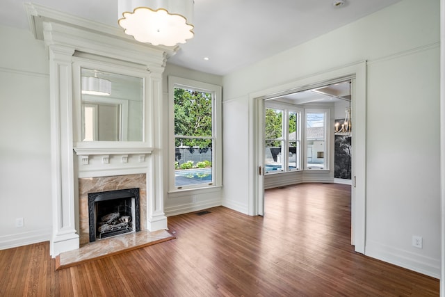 unfurnished living room featuring dark hardwood / wood-style flooring, a premium fireplace, and a healthy amount of sunlight