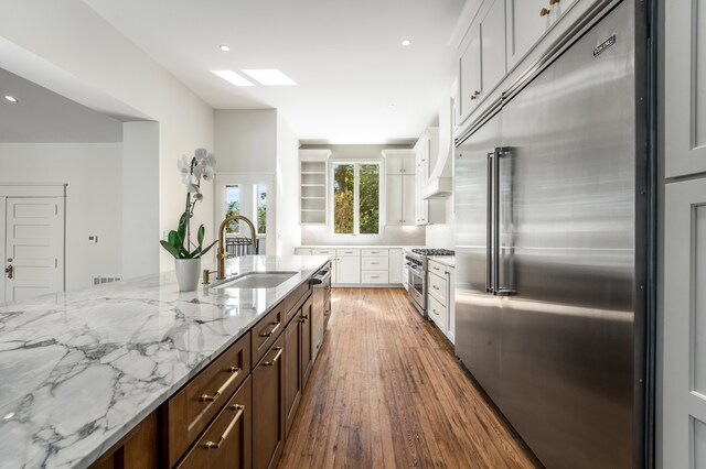 kitchen with white cabinets, high end appliances, dark hardwood / wood-style floors, and sink