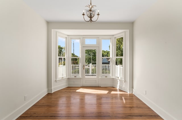 interior space featuring an inviting chandelier, a wealth of natural light, and dark hardwood / wood-style flooring