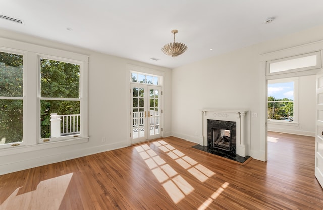 unfurnished living room with french doors, a healthy amount of sunlight, and light hardwood / wood-style flooring