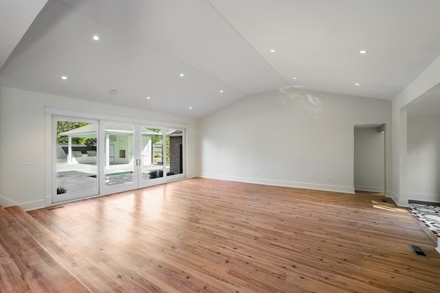 unfurnished living room featuring light hardwood / wood-style floors, french doors, and vaulted ceiling