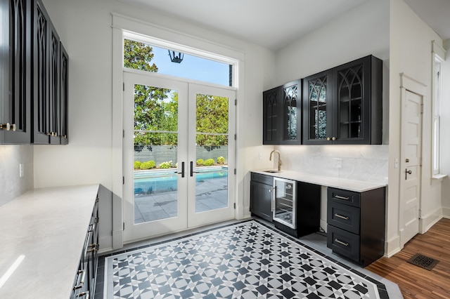 kitchen featuring french doors, wine cooler, dark wood-type flooring, backsplash, and sink