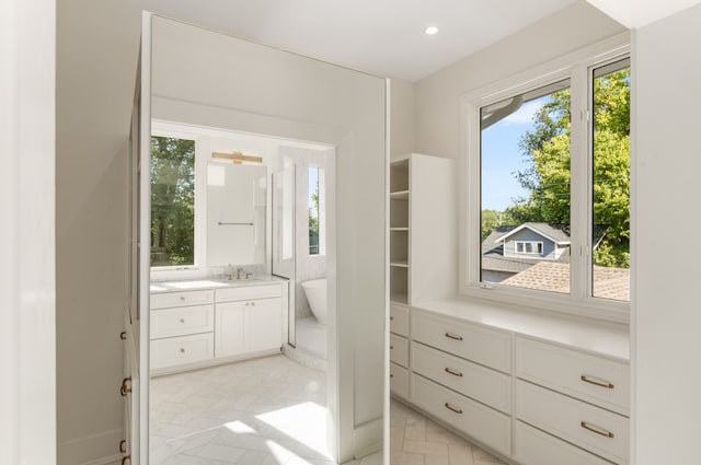 interior space with sink, ensuite bathroom, light tile floors, and multiple windows