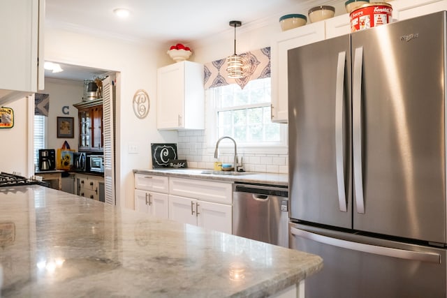 kitchen with decorative light fixtures, white cabinetry, appliances with stainless steel finishes, and light stone countertops