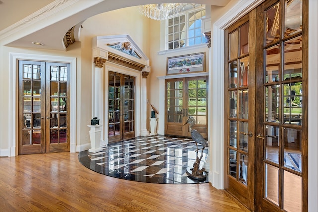 tiled foyer with a chandelier and french doors