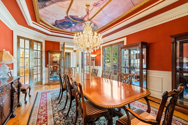 dining room featuring french doors, ornamental molding, a notable chandelier, and a tray ceiling