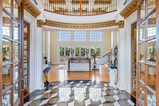 foyer featuring dark tile floors, decorative columns, a high ceiling, and french doors