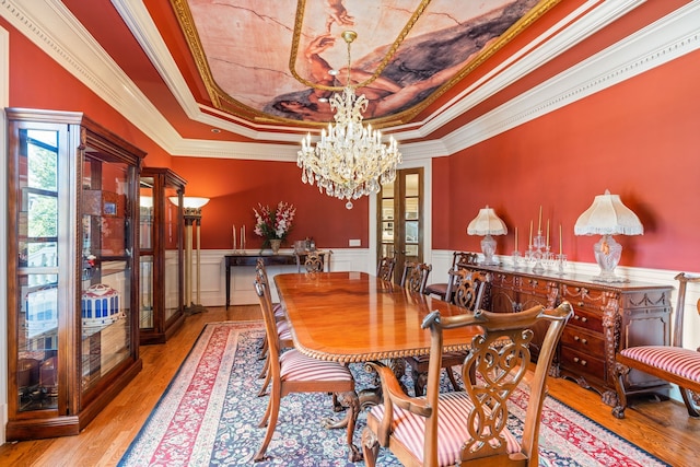 dining space with crown molding, a raised ceiling, a chandelier, light hardwood / wood-style flooring, and french doors