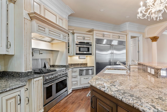 kitchen featuring decorative light fixtures, an inviting chandelier, high end appliances, hardwood / wood-style floors, and sink