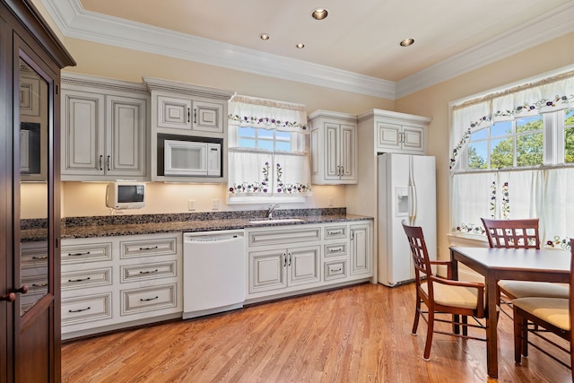 kitchen featuring white appliances, sink, light hardwood / wood-style flooring, dark stone countertops, and ornamental molding