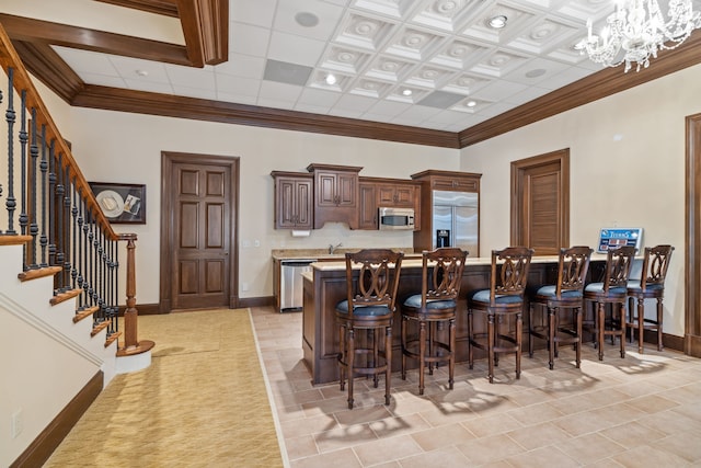 kitchen featuring a breakfast bar, a chandelier, stainless steel appliances, light tile flooring, and a center island