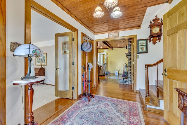 foyer featuring a chandelier, wooden ceiling, beamed ceiling, crown molding, and light wood-type flooring