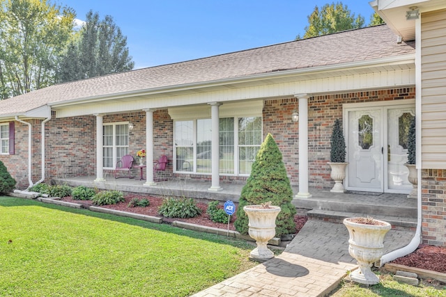 entrance to property featuring a lawn and covered porch