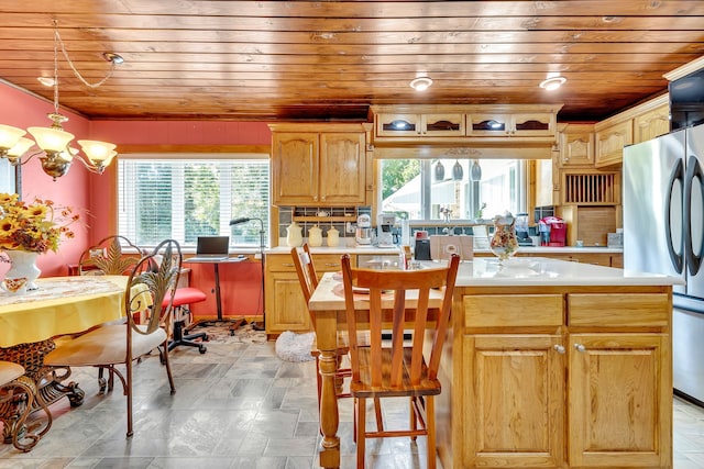 kitchen with a chandelier, a kitchen island, pendant lighting, stainless steel fridge, and light tile flooring