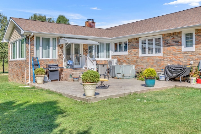 back of property with a lawn and a patio