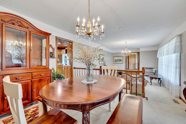 carpeted dining room featuring an inviting chandelier and a textured ceiling