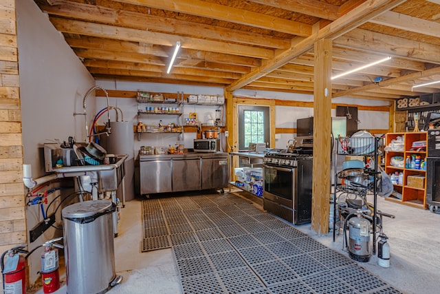 kitchen featuring stainless steel appliances, gas water heater, and concrete flooring