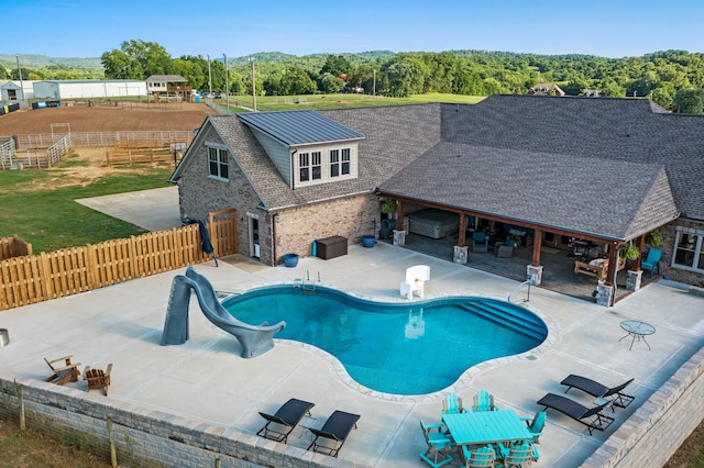 view of pool with a water slide and a patio area