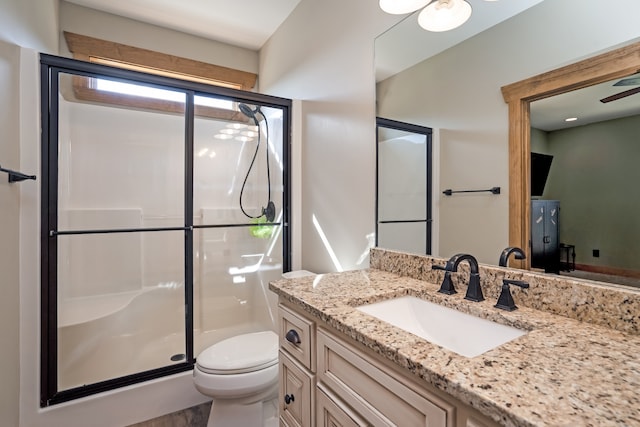 bathroom with vanity, ceiling fan, toilet, and an enclosed shower