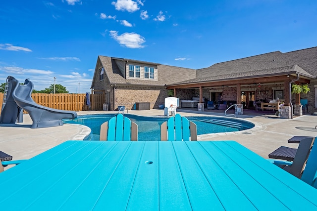 view of pool with a water slide and a patio area