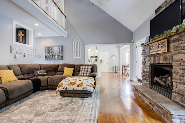 living room with a fireplace, high vaulted ceiling, and light wood-type flooring