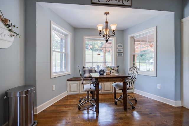 dining area with dark hardwood / wood-style floors and an inviting chandelier